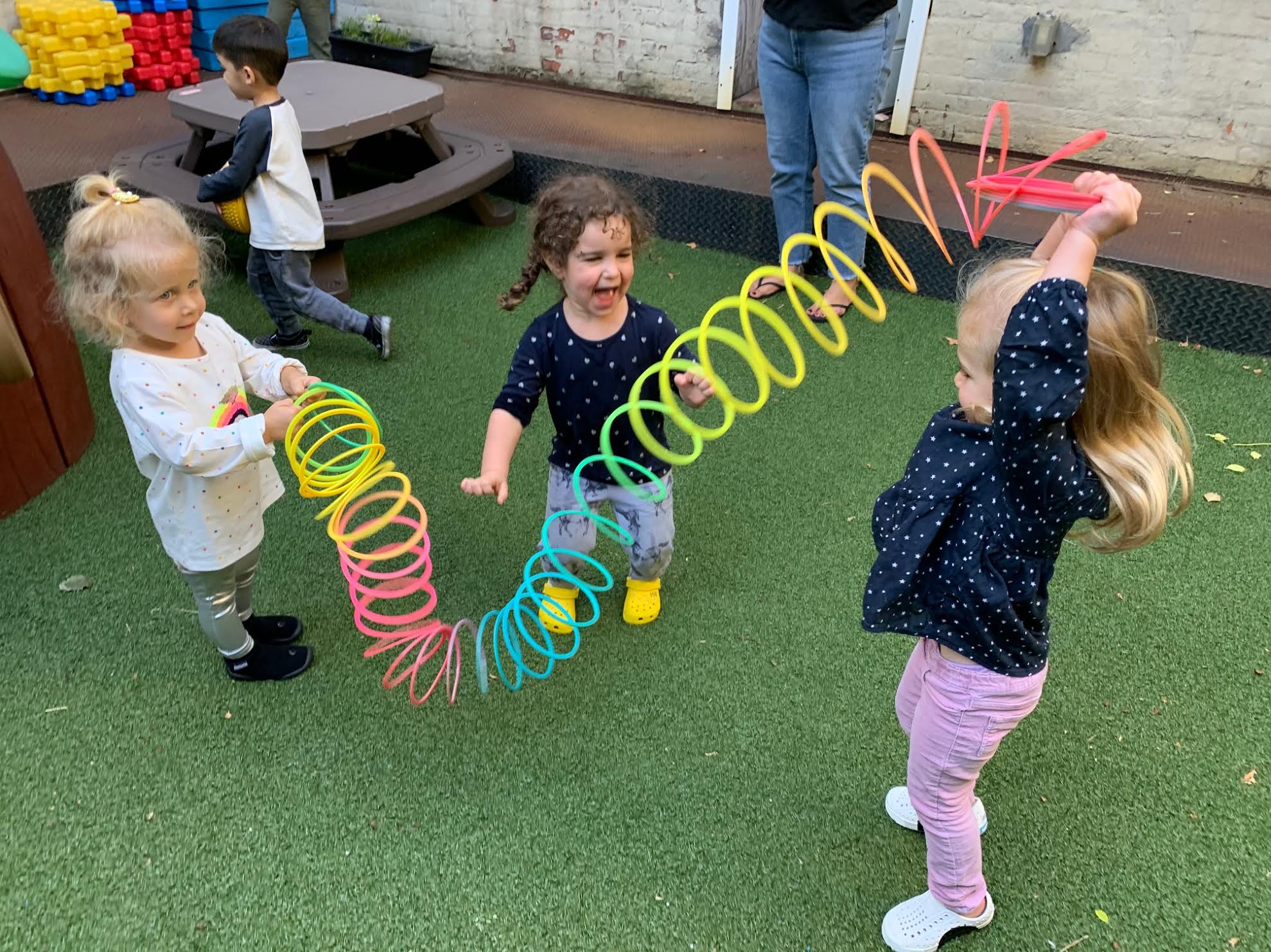 three young girls having fun with a very large slinky toy